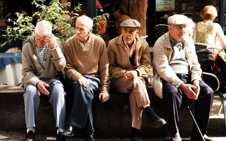 Hình ảnh một người đàn ông lớn tuổi đang thực hiện nghi lễ cúng bái trong một không gian u tối, xung quanh có khói hương