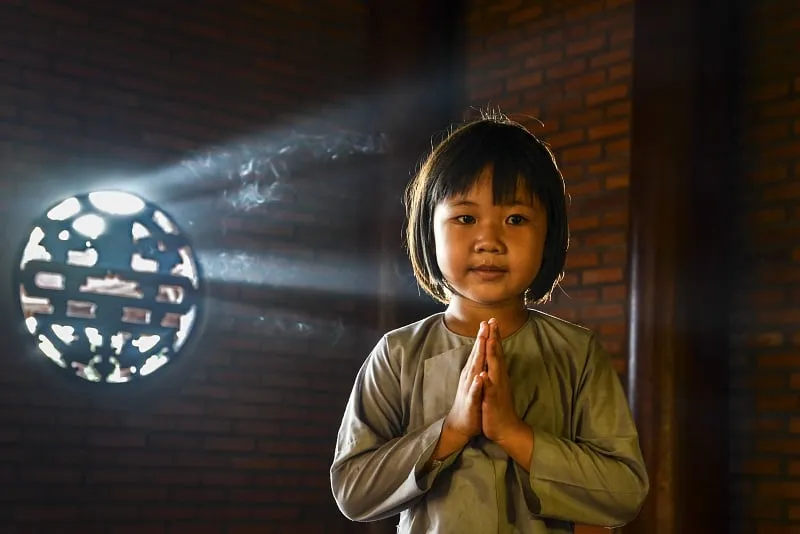 Trải nghiệm Phật Pháp của trẻ em: Một cậu bé đang chắp tay lạy Phật tại chùa